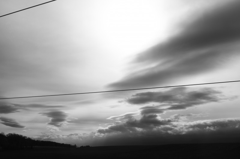 paysage en noir blanc, ciel nuageux, fils de trains barrant l'image