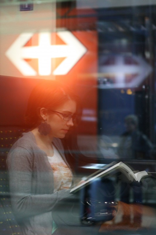 reflet dans la vitre d'un train, jeune femme lisant un livre